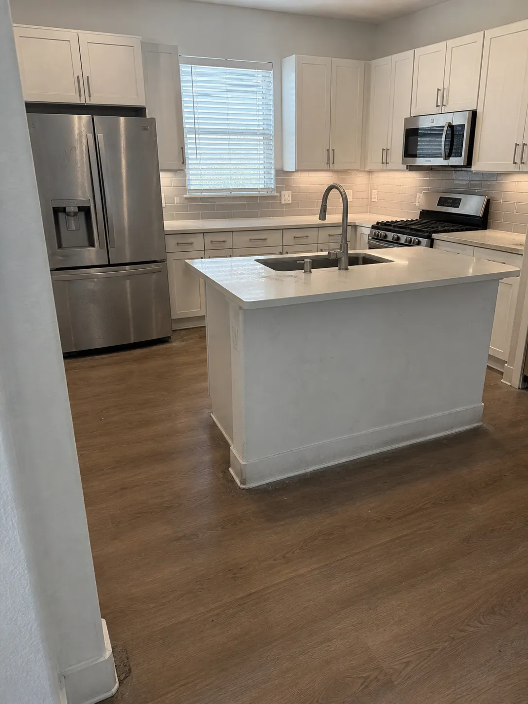 Kitchen floor, island, and appliances before cleaning